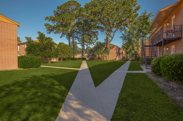 Sidewalks winding through a manicured lawn in front of brick apartment buildings.