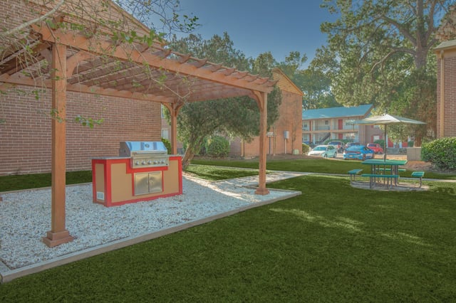 Outdoor grilling station with a built-in grill and a picnic table with an umbrella.