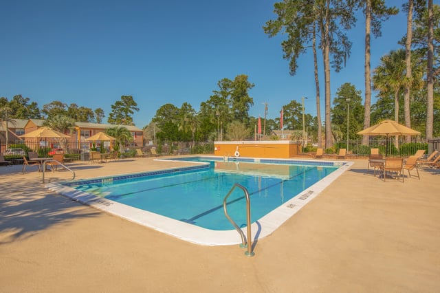 Outdoor swimming pool with lounge chairs and umbrellas.
