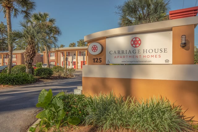 Carriage House Apartment Homes property signage and entrance with palm trees and landscaping.
