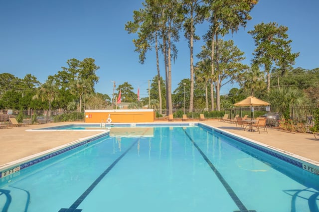 Outdoor swimming pool with lounge chairs and umbrellas.