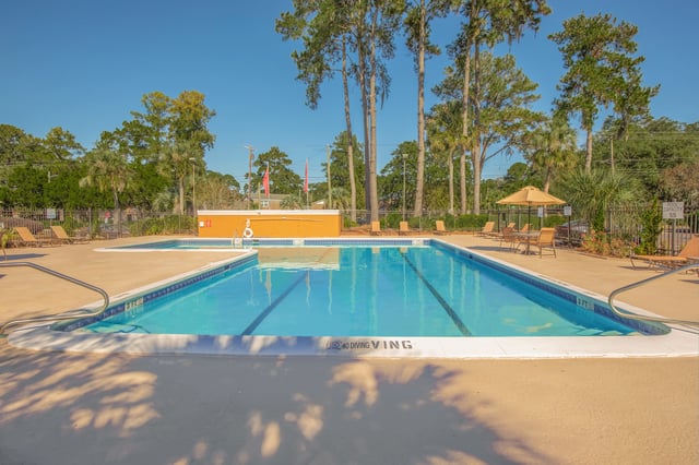 Outdoor swimming pool with lounge chairs and umbrellas.