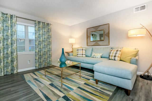 Light blue sectional sofa with decorative pillows on a rug in a living room.
