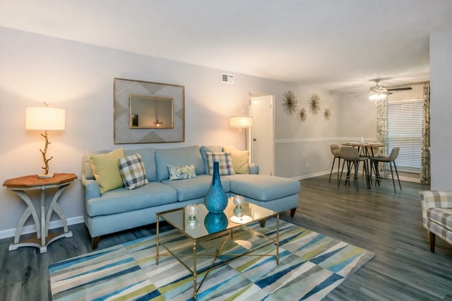 Living room with a blue sectional sofa, coffee table, and dining area.