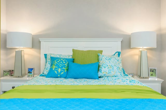 Comfortable bed with colorful pillows and lamps.