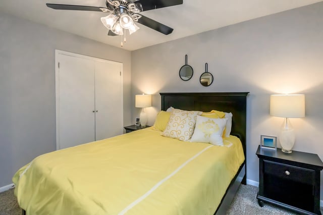 Bedroom with a queen-size bed, yellow bedding, and a ceiling fan.