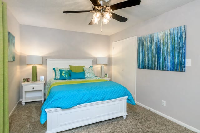 A bedroom with a king-size bed, nightstands, and a ceiling fan.