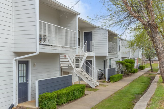 Exterior view of apartment buildings with white siding, dark doors, and white railings.