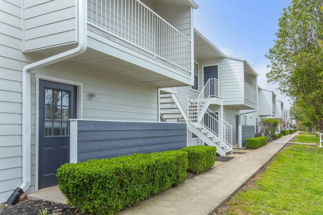 Exterior view of apartment buildings with white siding, dark blue doors, and white staircases.