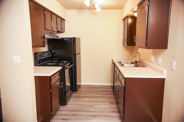 Kitchen with dark brown cabinets, stainless steel sink, and black appliances.