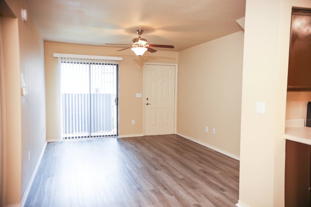 Living room with sliding glass door, ceiling fan, and entryway door.