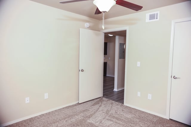 View of a bedroom with a ceiling fan and a doorway leading to the kitchen.