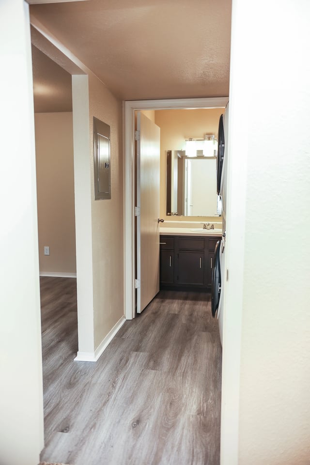 Hallway leading to a bathroom with a vanity and washer/dryer stack.