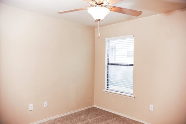 Empty bedroom with beige walls, carpet, ceiling fan, and blinds.