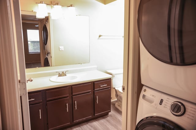 Bathroom with vanity, sink, toilet, and stacked washer/dryer.