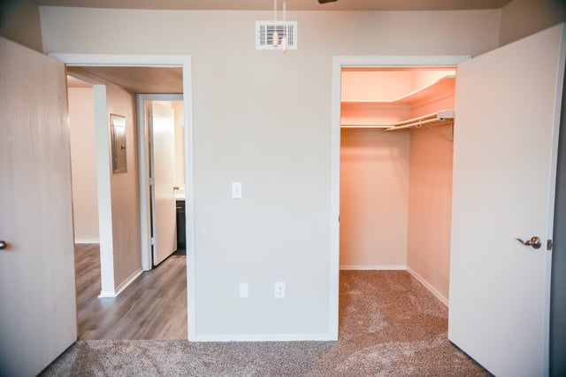 View of an empty bedroom with a closet and access to a bathroom.
