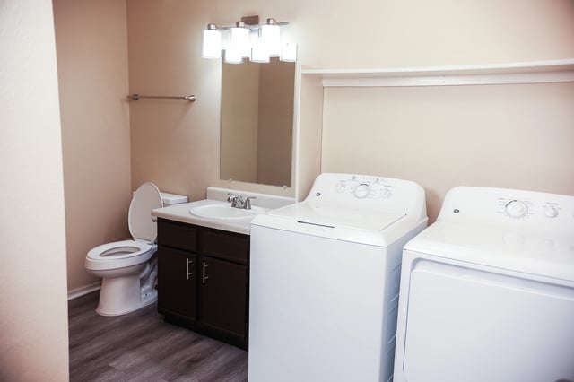 Bathroom with toilet, sink, and in-unit washer and dryer.