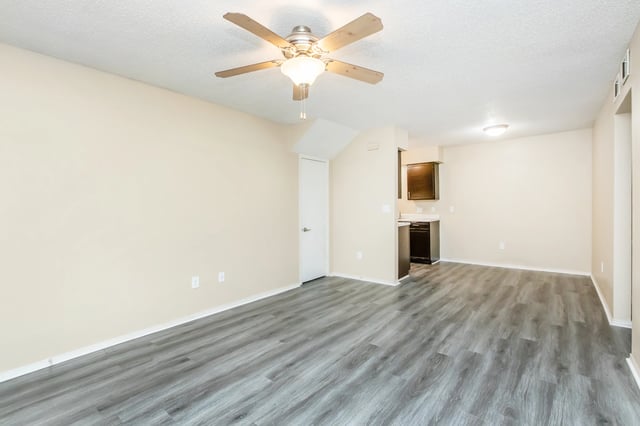 Empty living room with wood-look flooring and a ceiling fan.