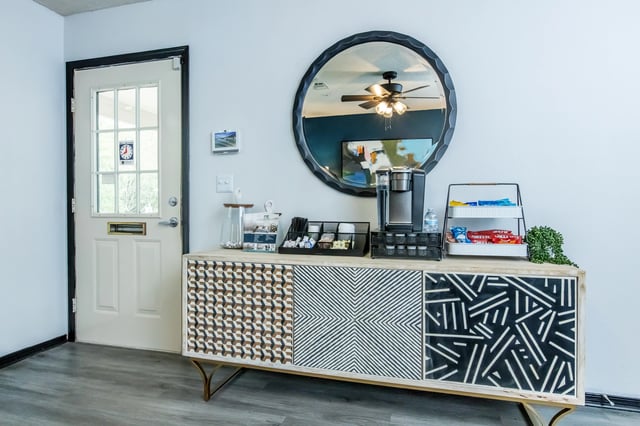 Coffee station with coffee maker, snacks, and a mirror in the lobby.
