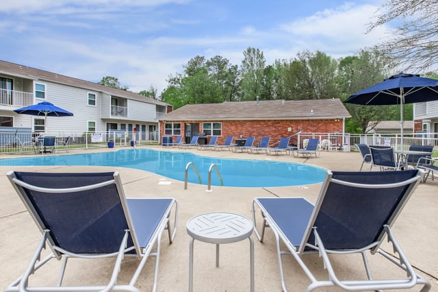 Resort-style swimming pool with lounge chairs and umbrellas.