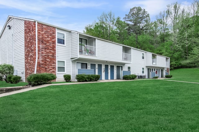 Exterior view of apartment buildings with manicured lawns and trees