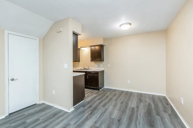 Kitchen and dining area with a white door and dark cabinets.