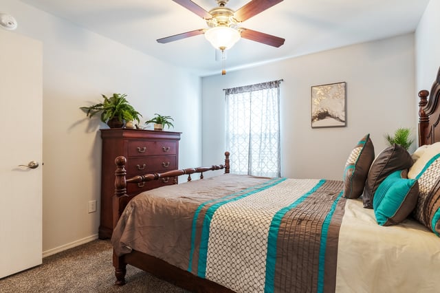 Bedroom with a queen-size bed, dresser, and ceiling fan.
