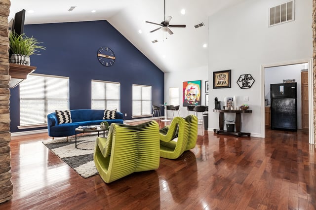 Modern lounge area with a blue sofa, unique lime green chairs, and a coffee station.