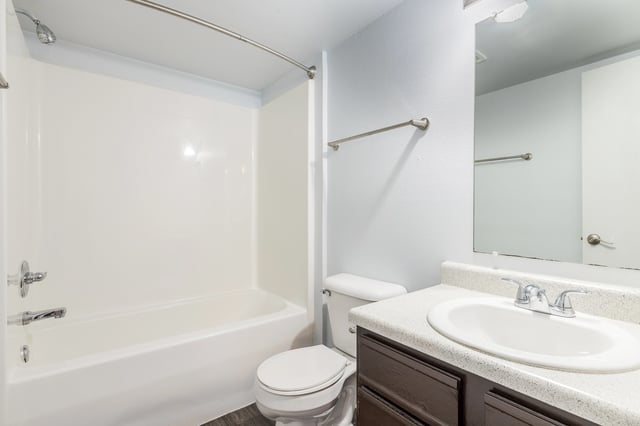Clean and bright bathroom with a white tub, toilet, and vanity with sink.