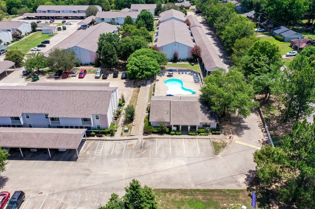 Aerial view of apartment complex with a swimming pool and lounge chairs.