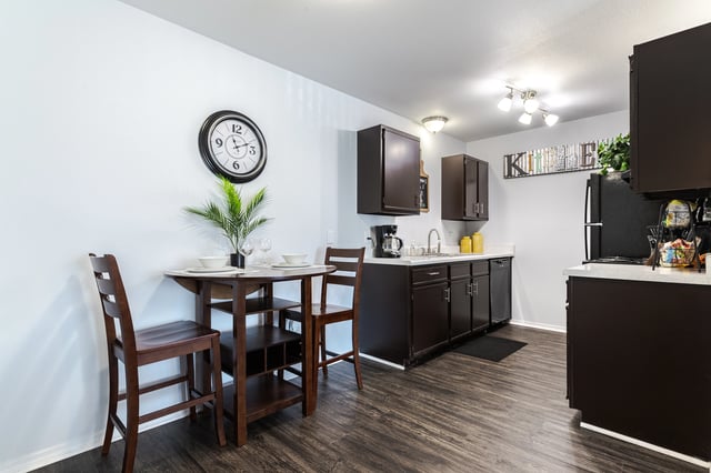 Kitchen and dining area with dark cabinets, a table with two chairs, and a refrigerator.