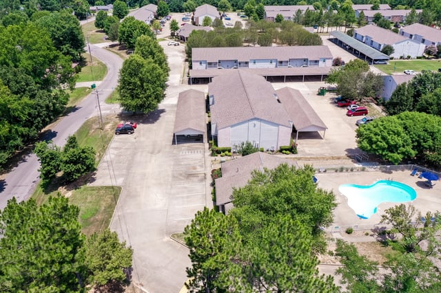 Aerial view of apartment buildings with a swimming pool and parking lot.
