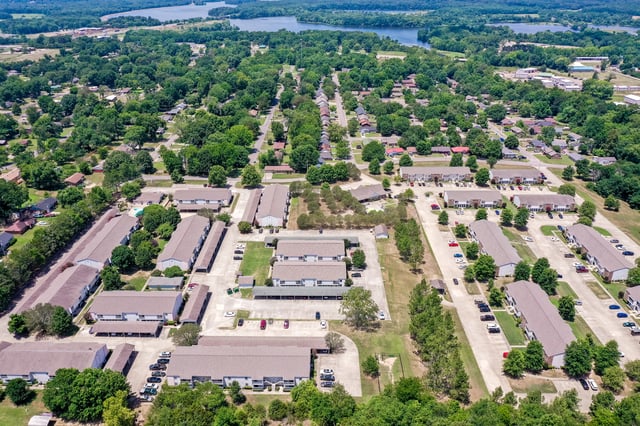 Aerial view of a multifamily property showing multiple apartment buildings, parking lots, and surrounding greenery.