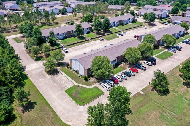 Aerial view of apartment buildings with parking lots and green spaces.
