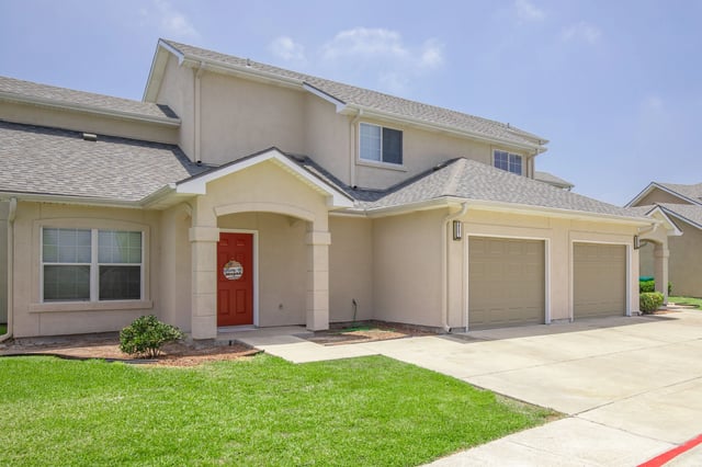 Exterior view of townhomes with garages and red front doors.