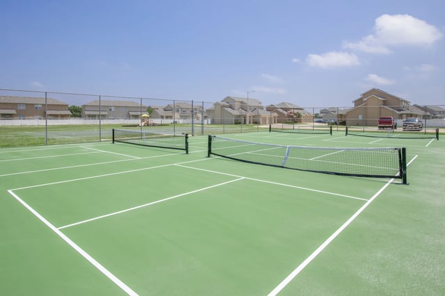 Tennis courts with nets and apartment buildings in the background.