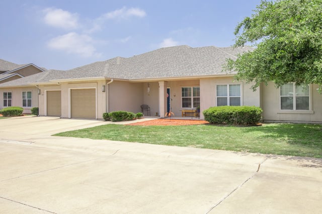 Exterior view of apartment buildings with garages and green lawns.