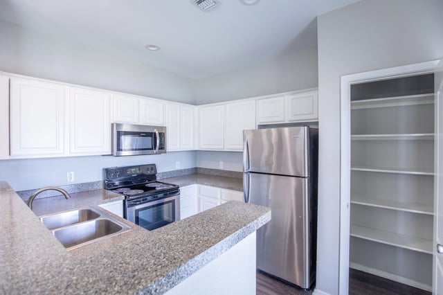 Modern kitchen with stainless steel appliances, white cabinets, and granite countertops.