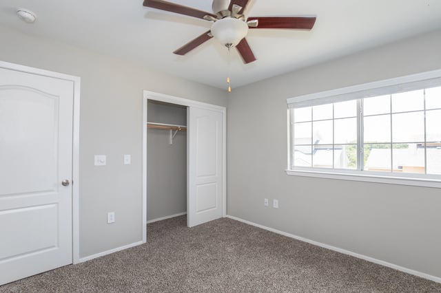 Bedroom with a ceiling fan, closet, and a large window.