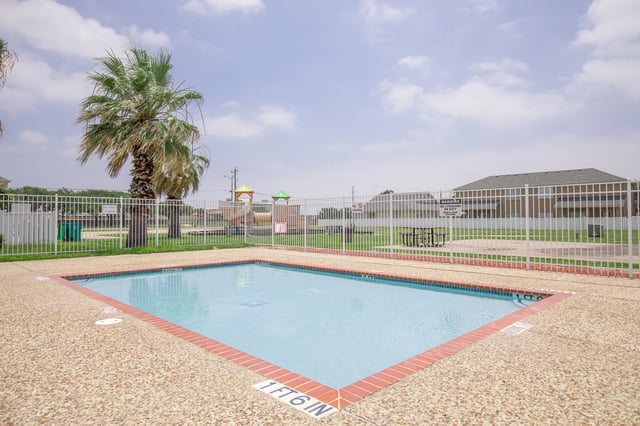 Swimming pool with a playground in the background.
