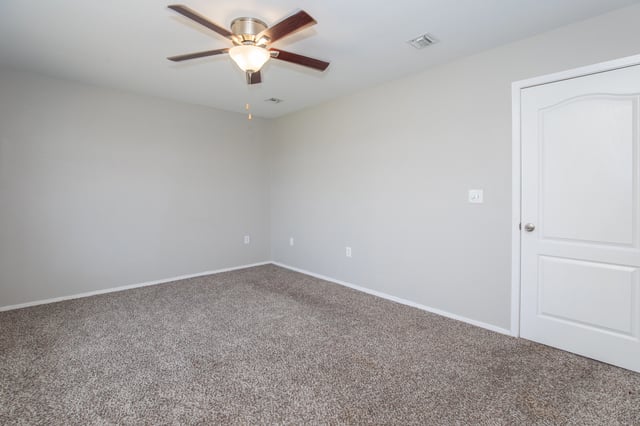 Bedroom with ceiling fan and neutral carpet.