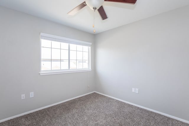 Bedroom with a ceiling fan and a large window.