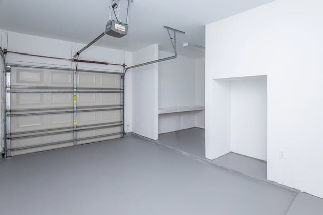 Empty garage with open door and storage shelves.