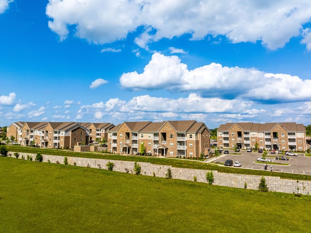 Exterior view of apartment buildings with balconies against a blue sky with white clouds.