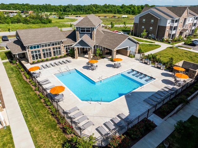 Resort-style swimming pool with lounge chairs and umbrellas, adjacent to apartment buildings.