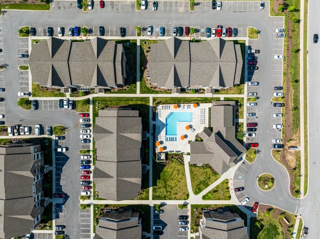 Aerial view of apartment buildings surrounding an outdoor swimming pool.