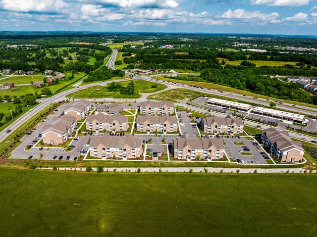 Aerial view of apartment buildings with surrounding landscape and highway