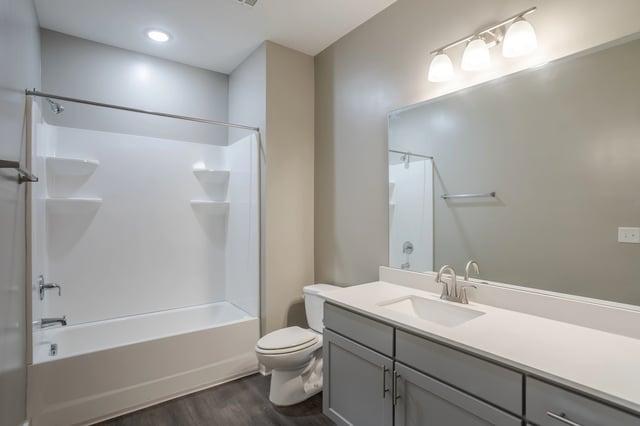 Modern bathroom with a white tub-shower combo, toilet, and vanity with a large mirror.
