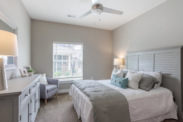 Cozy bedroom with a bed, dresser, and armchair.