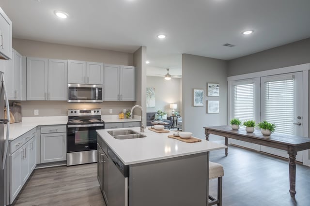 Modern kitchen with gray cabinets, stainless steel appliances, and a large island.